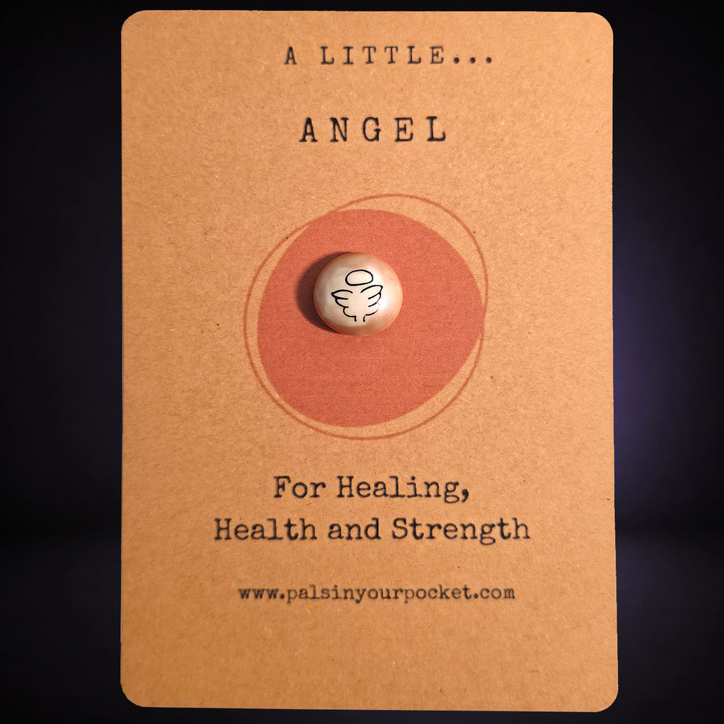 A pocket pal with angel illustration sits centered on a kraft paper backing card. The card has printed text reading 'A LITTLE ANGEL'
