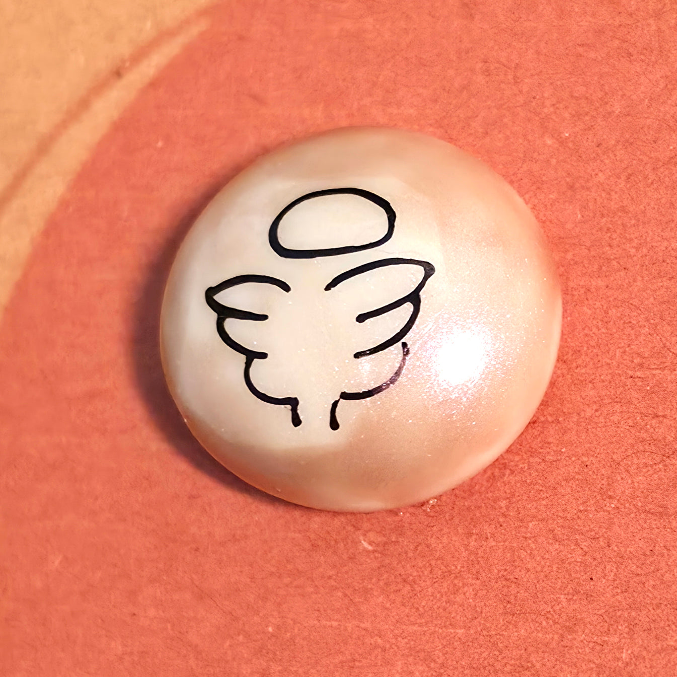 Close-up of Angel mindfulness pebble with wings symbol on supportive affirmation card about healing and strength.