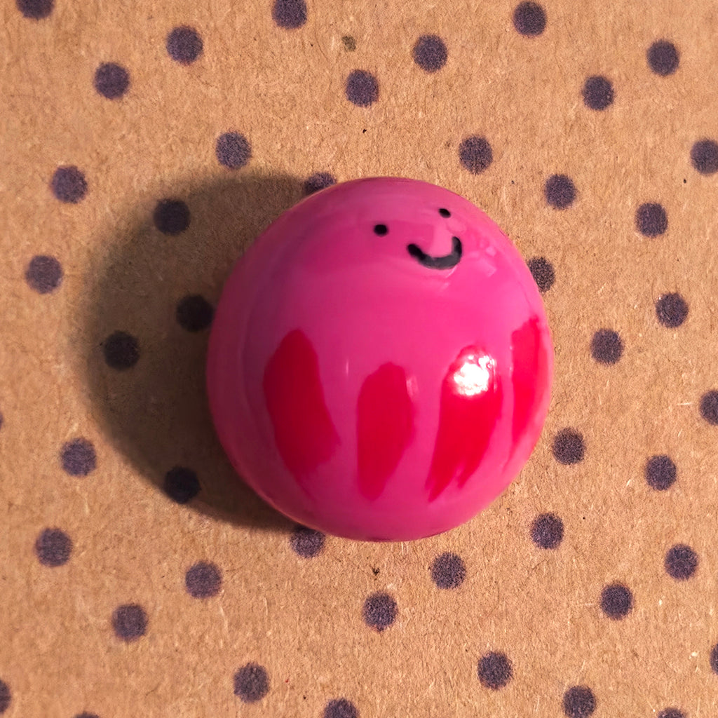 Close-up of Wobble mindfulness pebble with smiling face on supportive affirmation card about staying positive.