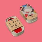 One sardine metal tins showing top and bottom of Bath Salts by Block Party on a solid pink background. Kraft paper band wrapped around it that reads 'SPAY DAY BATH SALTS'.