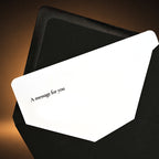 A white message card with the printed text 'A message for you' tucked inside a black envelope against a dark orange gradient background.