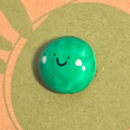 Close-up of Pea of Positivity mindfulness pebble with smiling green pea on cheerful affirmation card.