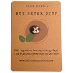 Slow Down But Never Stop mindfulness pebble with cute sloth face on motivational affirmation card.