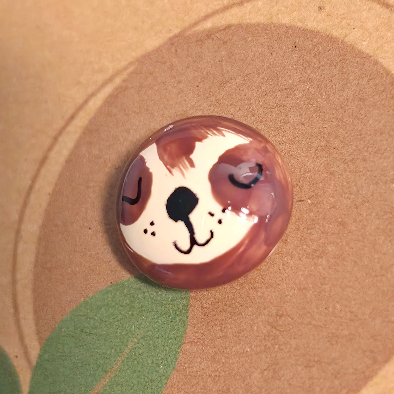 Close-up of Slow Down Never Stop mindfulness pebble with sleeping sloth face on uplifting affirmation card.