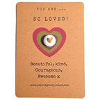 You Are So Loved mindfulness pebble with gold heart on affirmation card celebrating love and kindness.