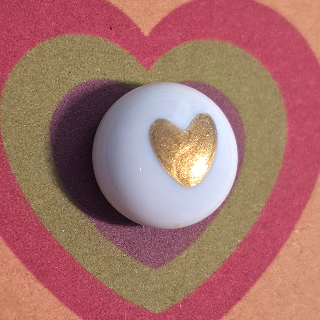 Close-up of So Loved mindfulness pebble with gold heart on heart-themed affirmation card about love and encouragement.
