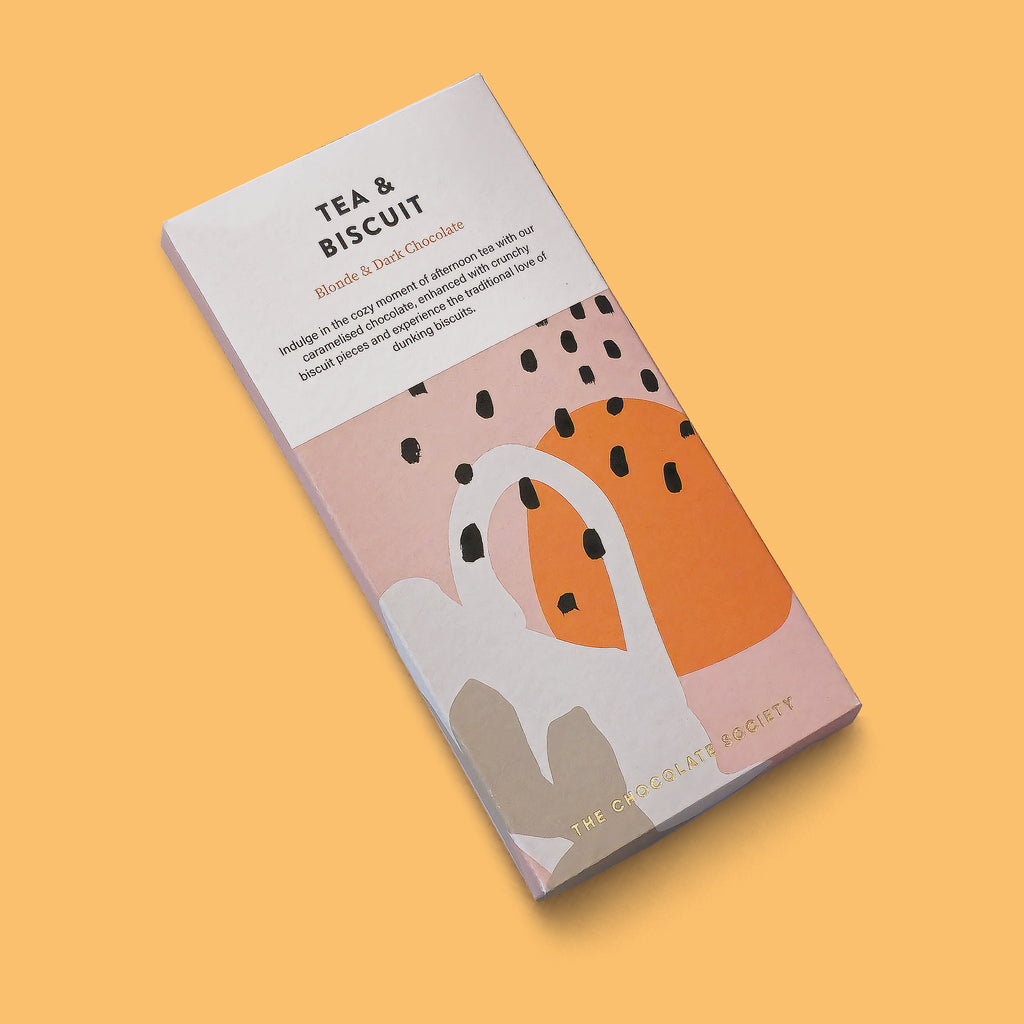 A chocolate bar package labelled 'TEA & BISCUIT' by The Chocolate Society, shown at an angle on a solid warm peach background. The box is mostly white with abstract blush pink, orange, gray, and black shapes, plus small text describing blend 6 dark chocolate.