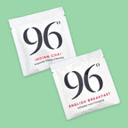 Two white tea sachets from the brand 96, one labeled 'Indian Chai' and the other 'English Breakfast', displayed diagonally on a solid light green background.