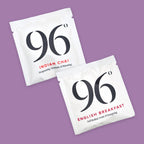 Two white tea sachets from the brand 96, one labelled 'Indian Chai' and the other 'English Breakfast', displayed diagonally on a solid purple background.