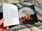 Open book with a fox illustration on a textured fabric background