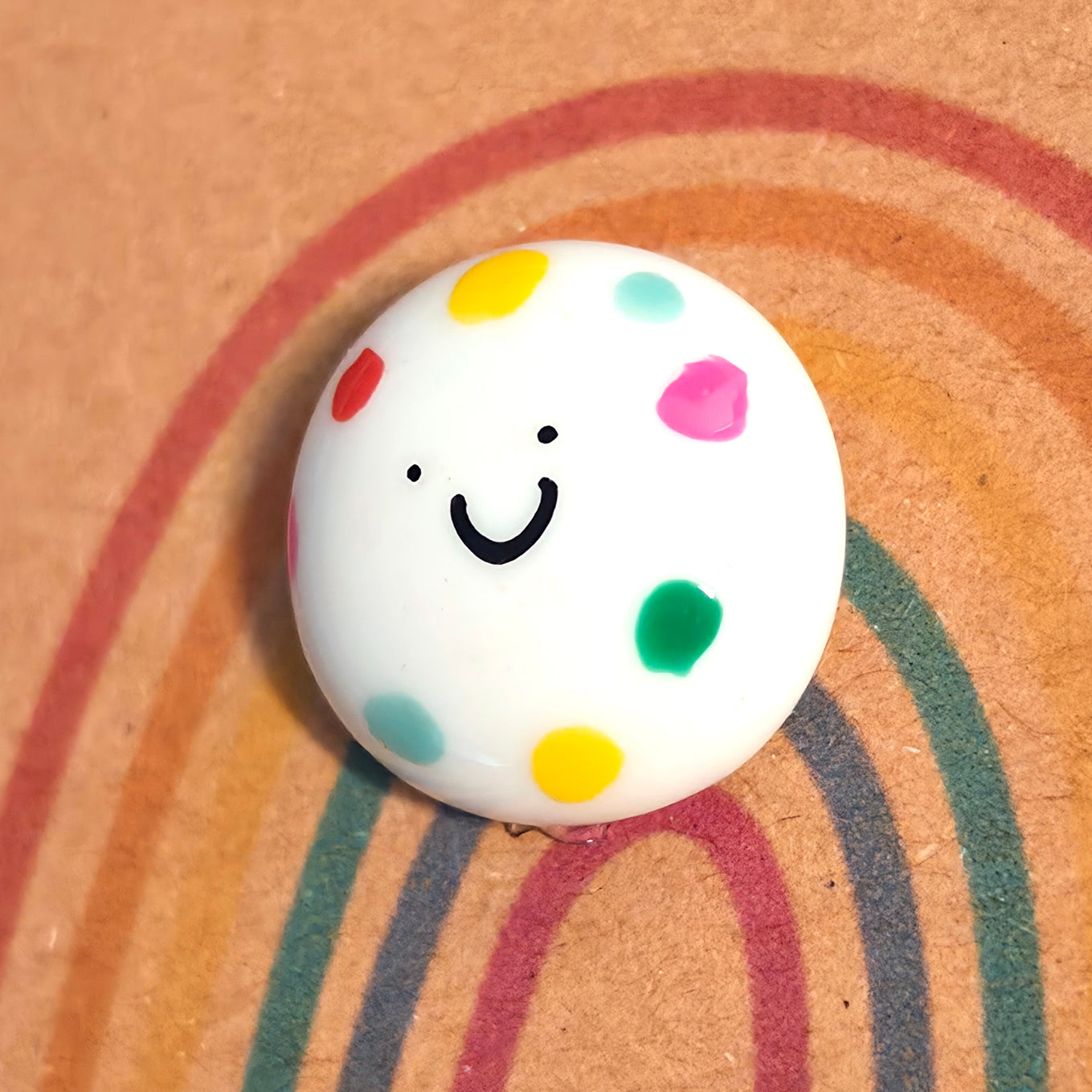 Close-up of You're Amazing mindfulness pebble with colourful dots on rainbow affirmation card about self-belief and positivity.