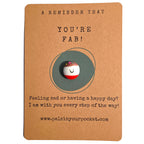A Reminder That You're Fab mindfulness pebble with smiling face on uplifting affirmation card.